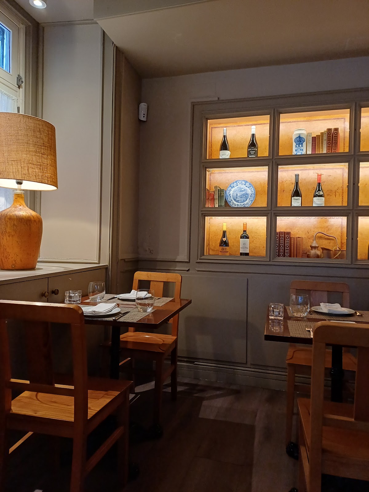Cozy restaurant dining corner with wooden tables and backlit wall shelves