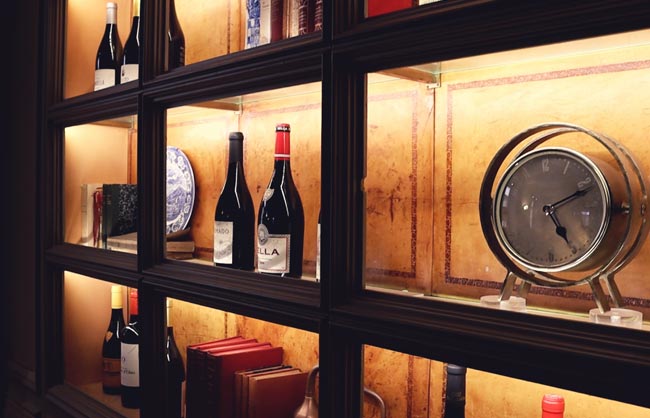 Backlit display cabinet with wine bottles, plates and books